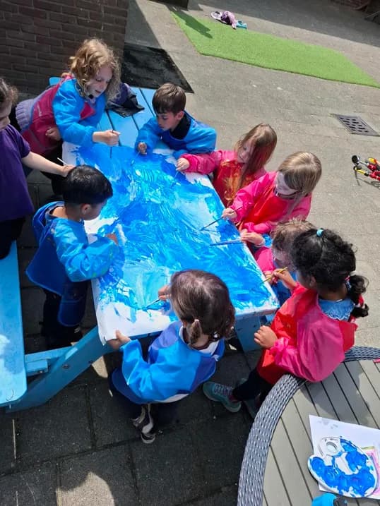 Students painting a large blue mural together outdoors