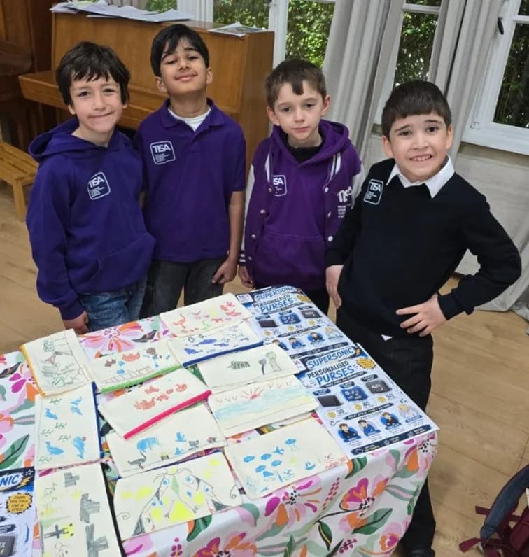 Four TISA Business students behind their hand-decorated purses for sale