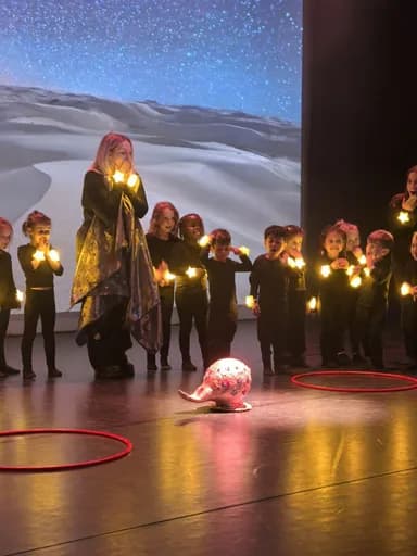 TISA students on stage holding glowing star props under a starry backdrop