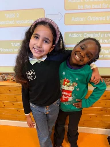 Two young students hugging warmly and smiling in the classroom